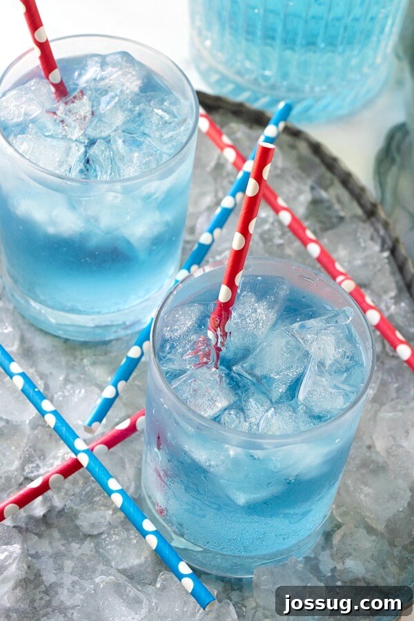 Craft Your Own Sonic Ocean Water 2 Two glasses of homemade Copycat Sonic Ocean Water on ice, garnished with lime slices, against a bright background.