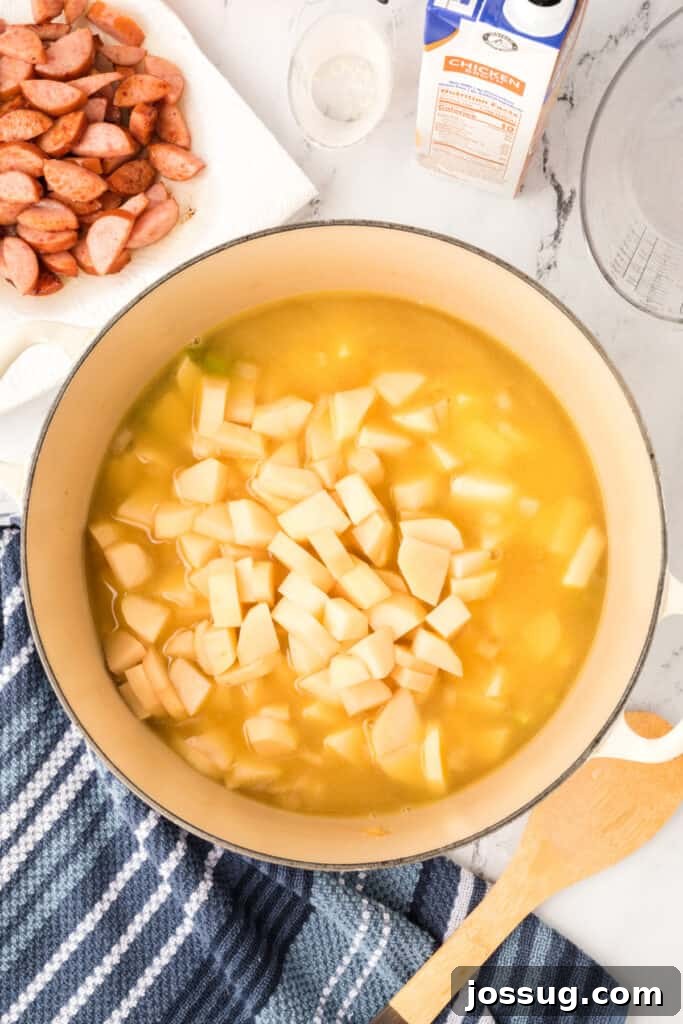 Cubed potatoes added into the simmering broth in the soup pot, ready to cook until tender.