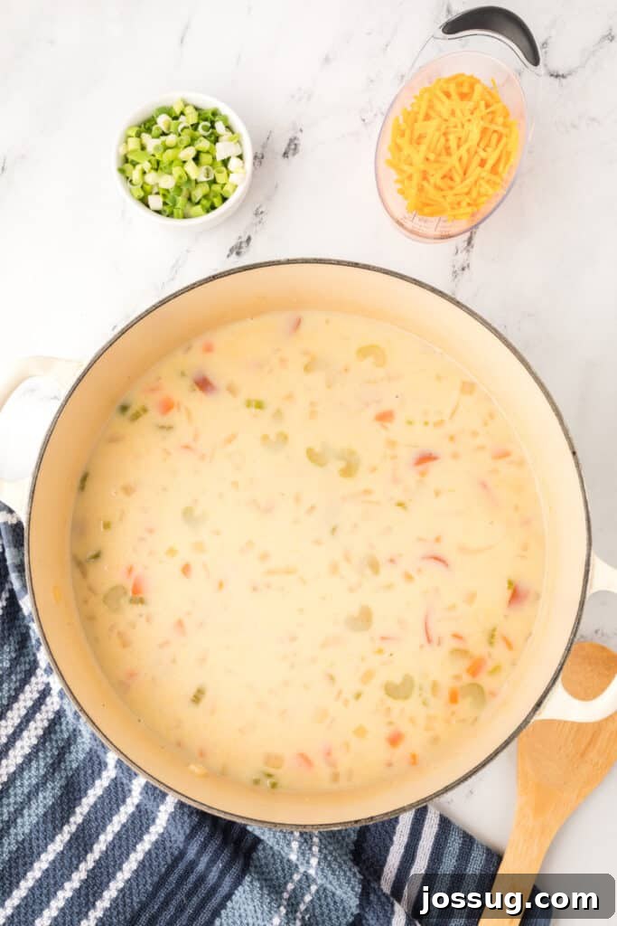 Pot of simmering cheesy kielbasa potato soup with a smooth, creamy broth.