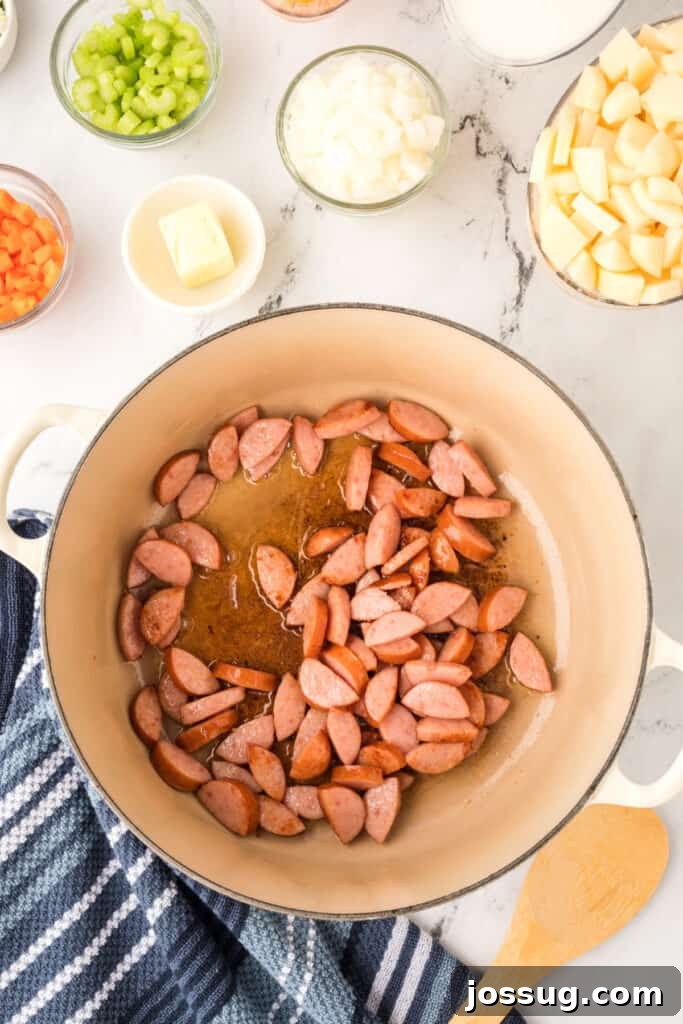 Browning kielbasa sausage pieces in a large pot with oil, giving them a golden color.