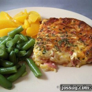 Cheesy Ham & Egg Bake 2 A freshly baked, golden-brown Crustless Ham Savory Bake, garnished with fresh parsley.
