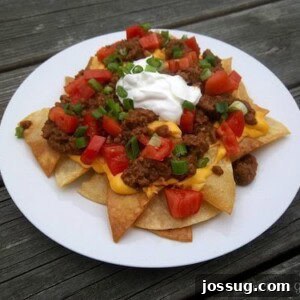 Beefy Bean Fiesta Nachos 2 Loaded Beef and Bean Nachos served on a plate with various toppings.
