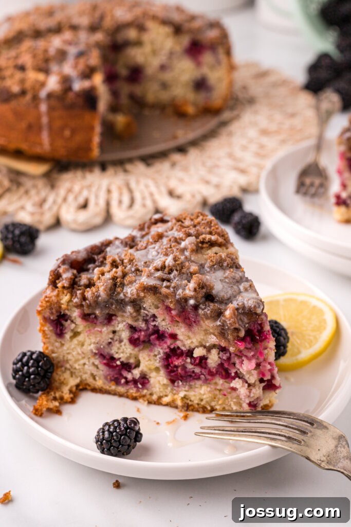 Slice of blackberry lemon coffee cake on a white plate with fresh blackberries