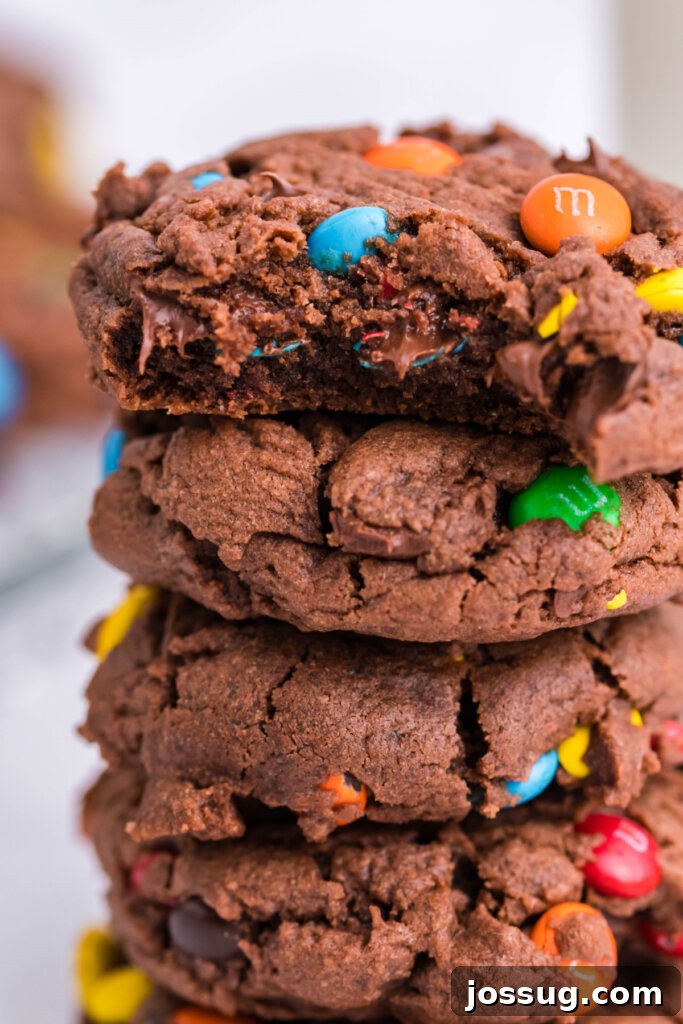 Stack of soft, colorful M&M Chocolate Pudding Cookies with a sprinkle of M&Ms around them, highlighting their appealing texture and vibrant look.