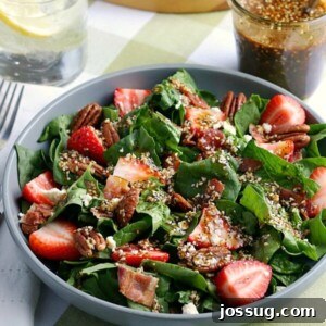 Sweet & Tangy Strawberry Spinach with Balsamic Poppy Glaze 2 A vibrant Strawberry Spinach Salad with fresh ingredients and a drizzle of homemade dressing, presented in a large white bowl.