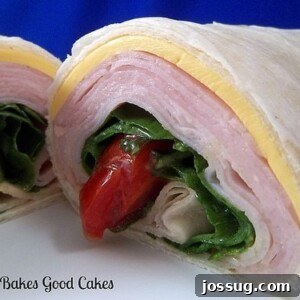 Savory Turkey Spinach Roll-Ups 2 A freshly made Turkey Spinach Wrap, cut in half and showcasing layers of turkey, fresh spinach, cheese, and tomato inside a soft tortilla.