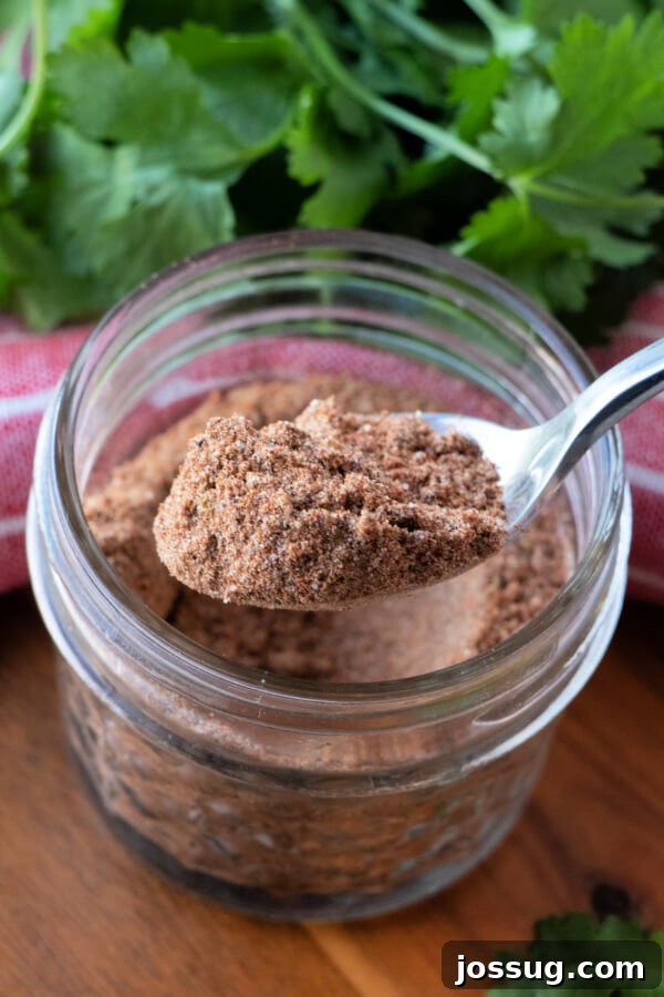 DIY Taco Spice Mix 8 A spoon overflowing with homemade taco seasoning held over a jar filled with the spice blend