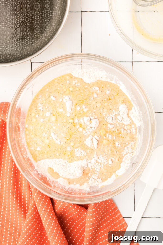Mixing bowl with wet ingredients poured over dry mixture for pumpkin pancake batter