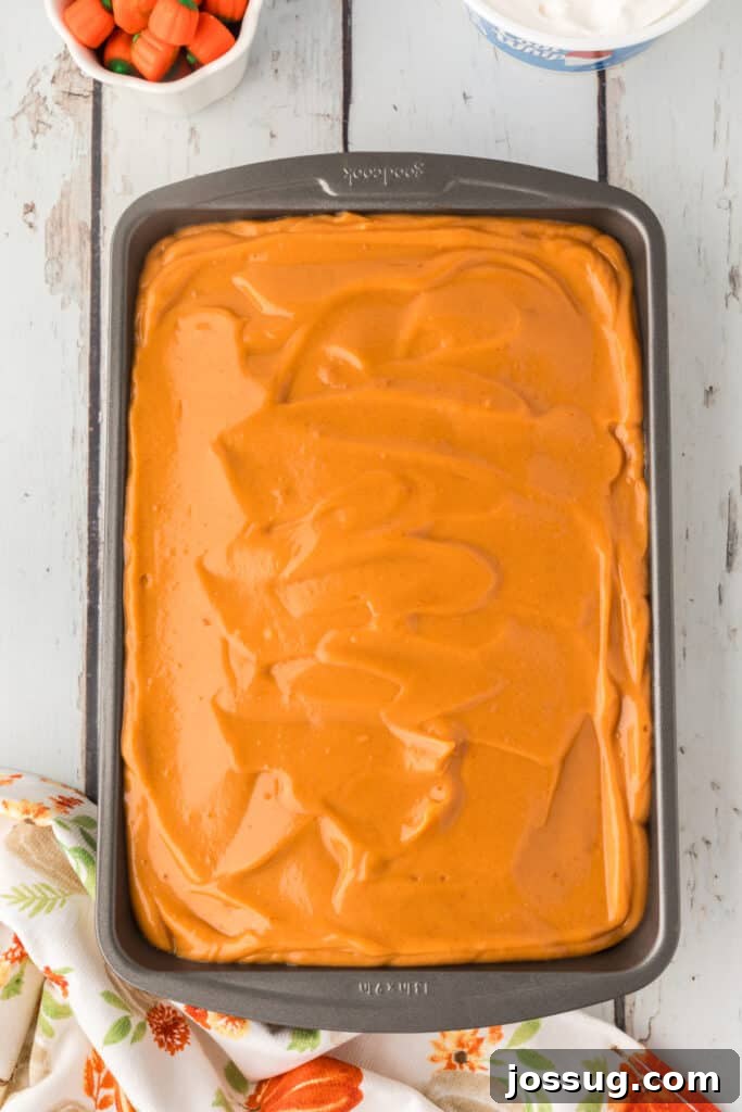 Decadent Pumpkin Spice Poke Cake 11 Pudding spread over the poked cake, ready to chill