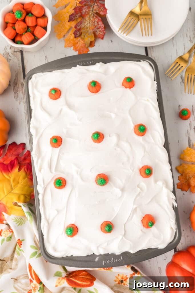 Decadent Pumpkin Spice Poke Cake 14 Pumpkin poke cake topped with candy pumpkins and surrounded by fall decor