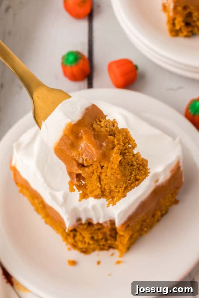 Decadent Pumpkin Spice Poke Cake 15 Fork holding a bite of pumpkin poke cake with pudding and whipped topping