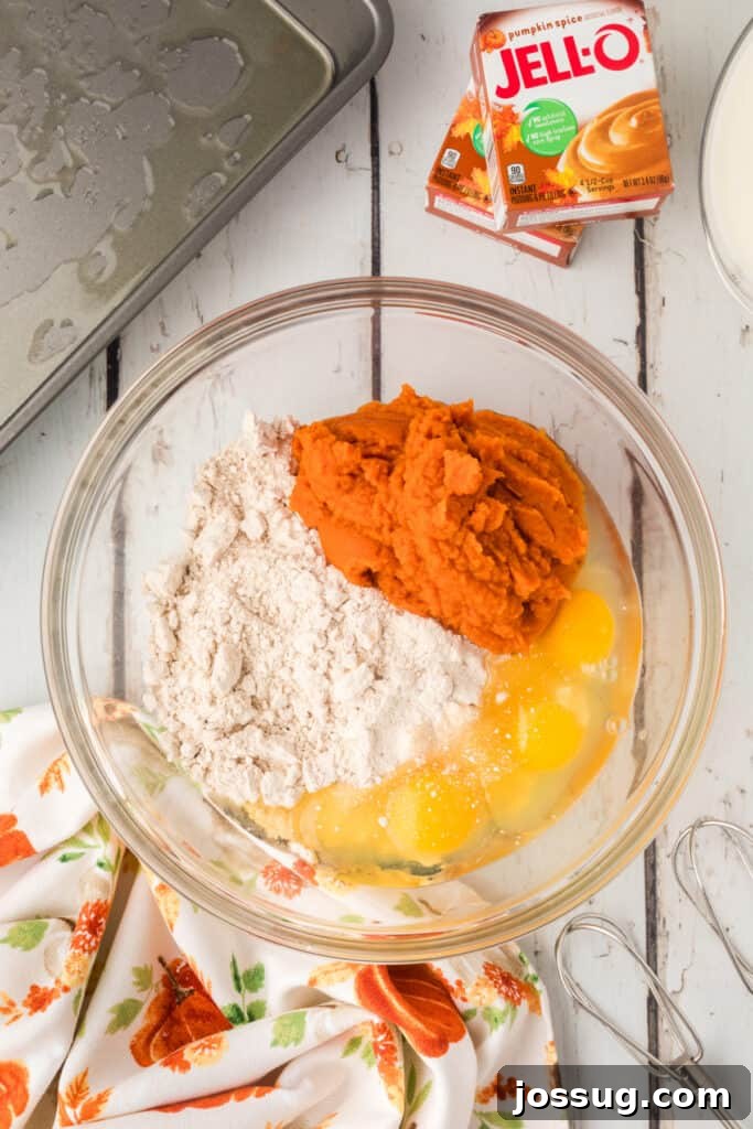 Decadent Pumpkin Spice Poke Cake 4 Mixing bowl with eggs, pumpkin, and spice cake mix ready to be blended