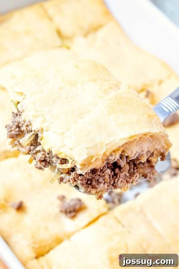 A slice of homemade White Castle Casserole being lifted with a spatula, showcasing the cheesy, meaty layers.