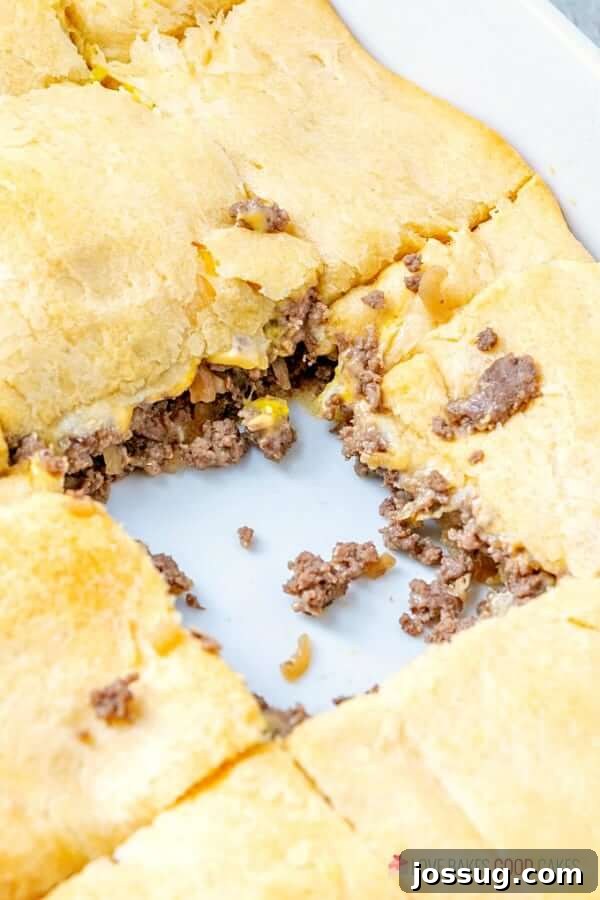 A baking dish filled with White Castle Casserole, with a single piece removed from the center, revealing the gooey cheese and beef interior.