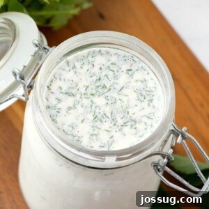 Whip Up Your Own Irresistible Ranch 2 Looking down into a glass container with homemade ranch dressing, garnished with fresh herbs.