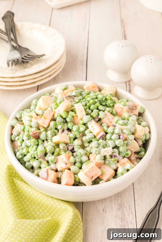 Velvety Pea Salad 3 An overhead shot of a large white serving bowl filled with a generous portion of creamy pea salad, garnished with fresh herbs.