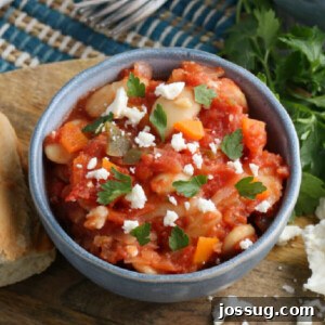 A blue bowl with Greek Baked Beans topped with Feta cheese, a perfect, comforting dish
