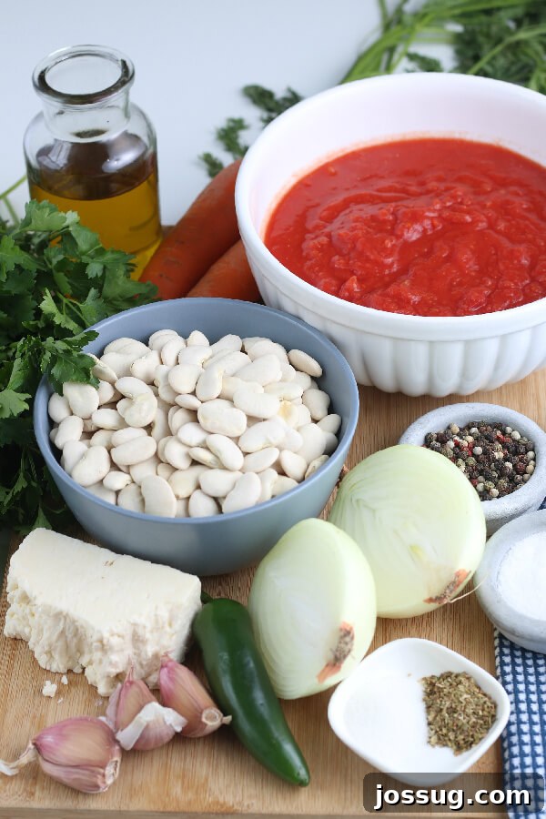 Essential ingredients laid out for making this authentic Greek baked beans recipe, including dried beans, fresh vegetables, and herbs