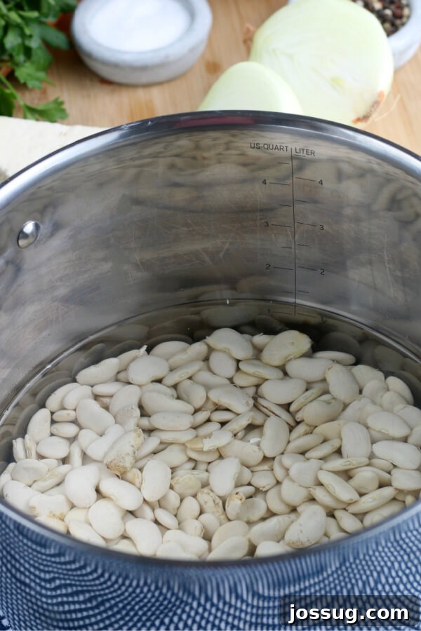 Dried butter beans soaking in a large pot of water, a crucial step for achieving tender baked beans