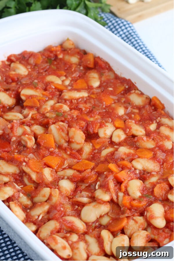 The Greek Baked Beans casserole in a baking dish before being placed in the oven, showing the bean and sauce mixture