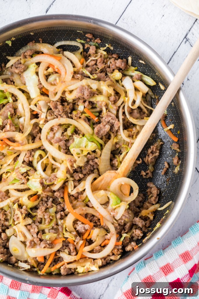 Close-up shot of the savory Asian pork and vegetable filling simmering in a skillet, ready to be wrapped into burritos.