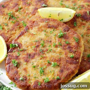 several salmon patties on a white serving platter with lemon wedges