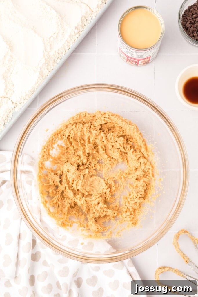 Creamed butter and brown sugar mixture in a clear glass bowl, showcasing its light and fluffy texture after blending.