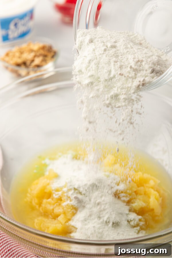 Green Jewel Salad 3 Instant pistachio pudding mix being poured into a bowl of crushed pineapple, illustrating the first step of preparation.