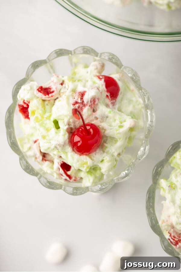 Green Jewel Salad 6 A finished bowl of creamy green pistachio salad, garnished with a few whole maraschino cherries, ready to be served.