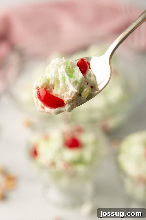 Green Jewel Salad 7 A spoonful of creamy green pistachio salad with visible marshmallows, pineapple, and nuts, showcasing its texture.
