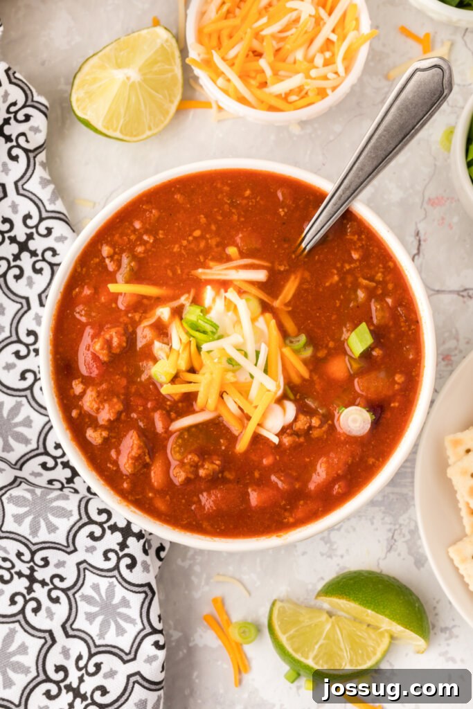 A steaming bowl of homemade Copycat Wendy's Chili, garnished with shredded cheese and a sprinkle of fresh green onions, ready to be enjoyed.