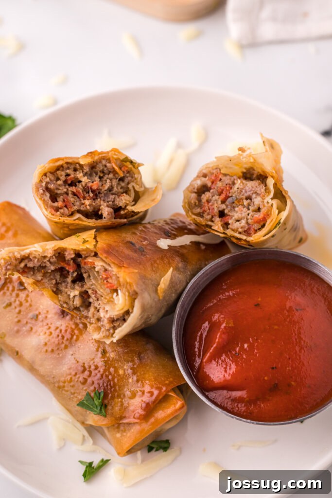 Closeup of homemade pizza rolls showing the delicious filling, with pizza sauce on the side for dipping