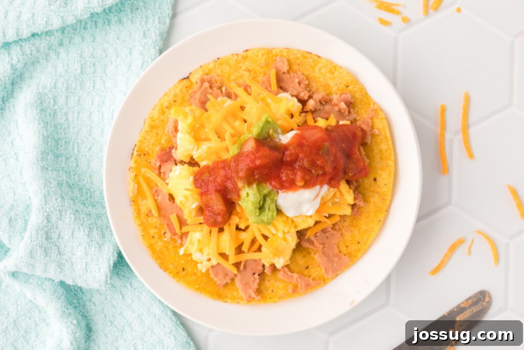 Crispy Morning Fiesta 5 Overhead shot of a single breakfast tostada on a white plate, showcasing the vibrant colors of the toppings against the crispy shell.