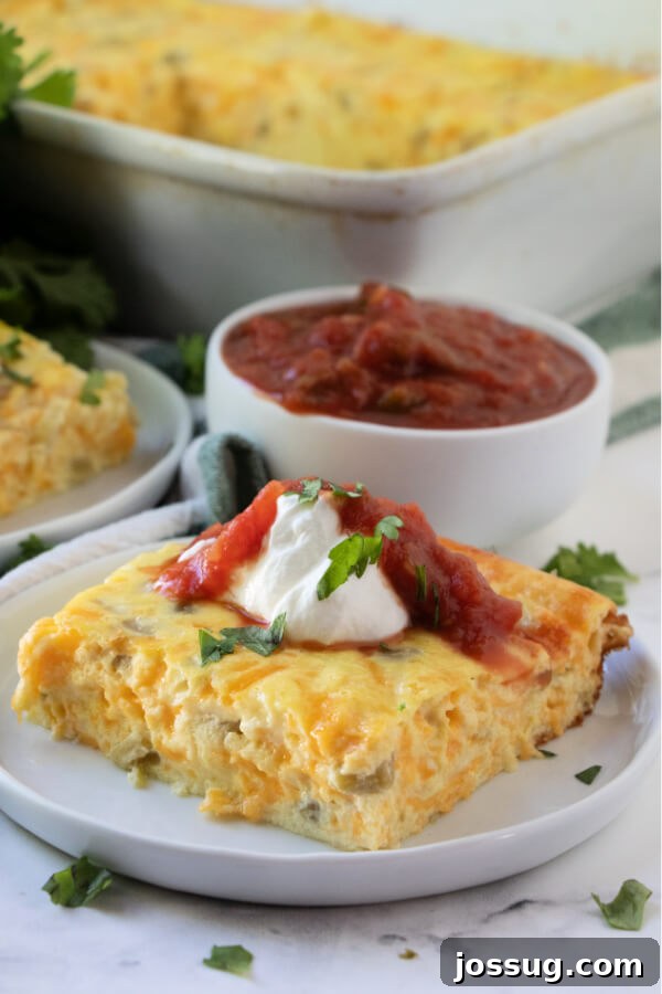 A golden-brown slice of Chili Rellenos Bake, garnished with fresh cilantro, on a white plate, ready to be enjoyed.