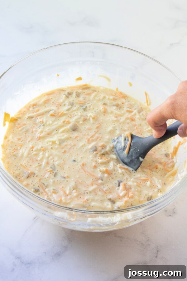 All the Chili Rellenos Bake ingredients perfectly mixed in a large bowl, ready to be poured into the baking dish.