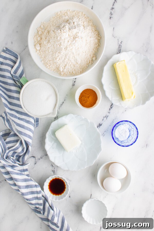 A beautiful spread of fresh ingredients for baking Snickerdoodles, including softened butter, eggs, flour, sugar, and a bowl of cinnamon.
