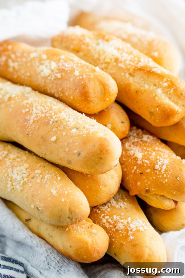 A basket overflowing with golden-brown Soft Italian Breadsticks, ready to be enjoyed.