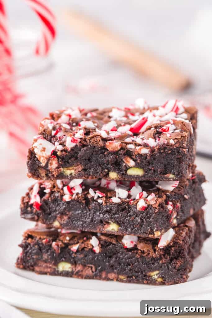 Candy Cane Swirl Brownies 2 A tempting stack of three fudgy Candy Cane Brownies on a white plate, showcasing the peppermint pieces and mint chips within.