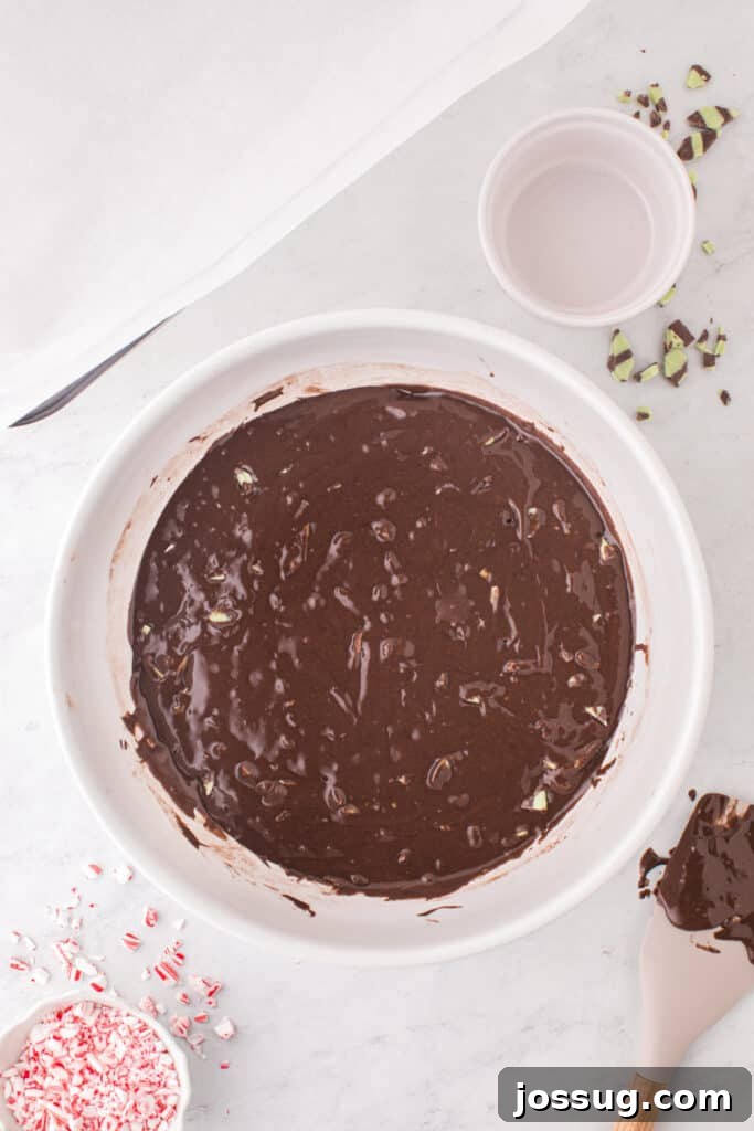 Candy Cane Swirl Brownies 6 Brownie batter mixed with mint fudge baking chips in a white bowl, ready to be poured into the baking pan.