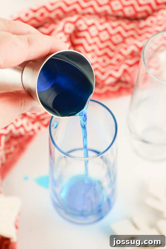 Pouring blue curacao into a champagne glass