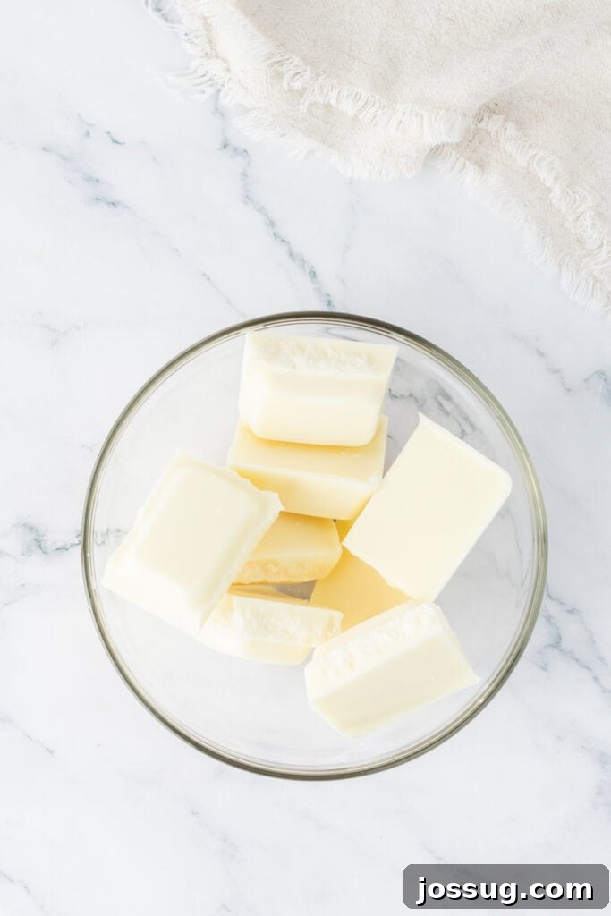 Chunks of white chocolate or candy coating in a glass bowl, ready to be melted for pink Valentine truffles.