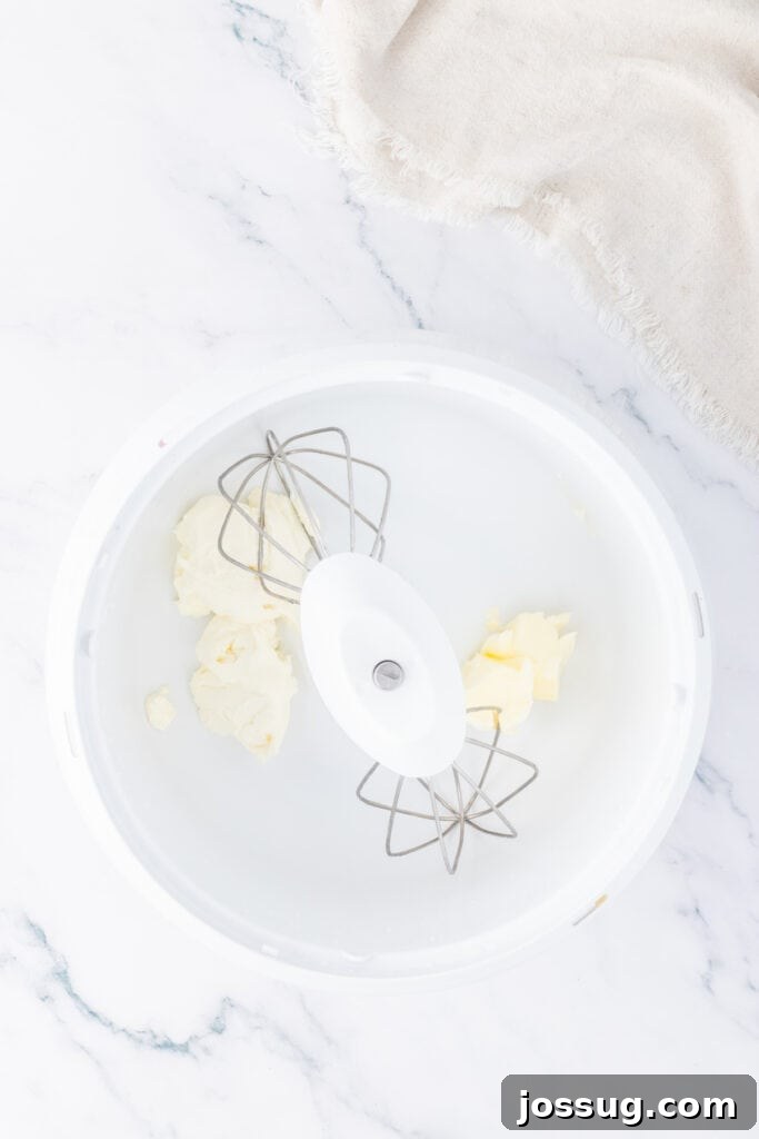 Butter and cream cheese in a mixing bowl with beaters attached, ready to be whipped for the truffle filling.