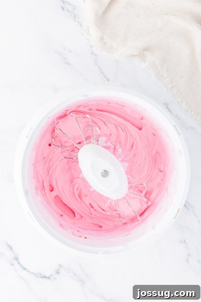 Pink frosting being whipped in a mixing bowl until smooth and fluffy for coating the truffles.