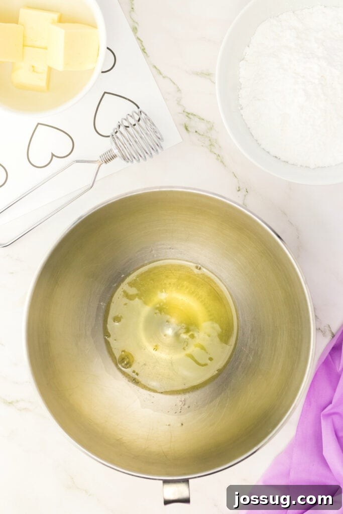 Egg whites in a metal mixing bowl before whipping into meringue.