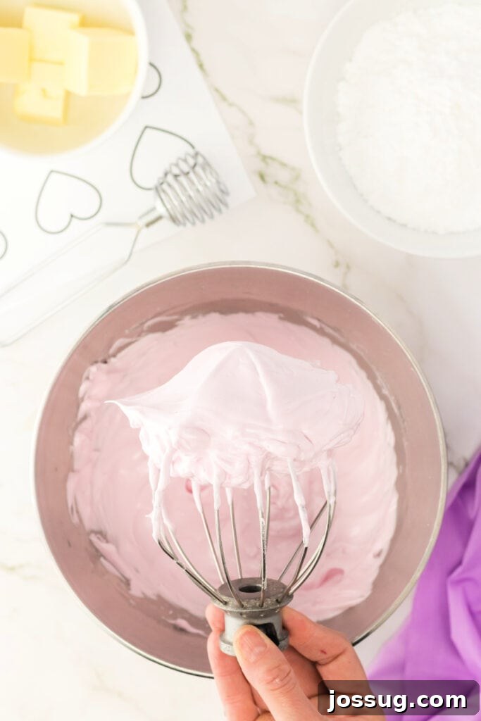 Pale pink macaron batter whipped to stiff peaks on a whisk attachment.