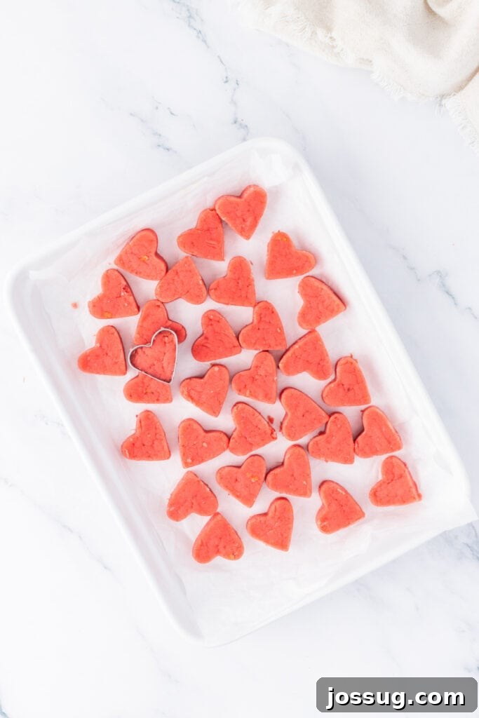 Strawberry Cream Truffle Hearts 11 Heart-shaped strawberry cake truffles cut and arranged on a parchment-lined tray before dipping