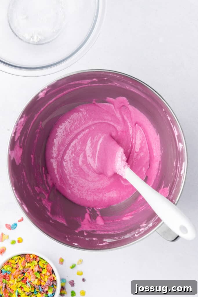 Pink macaron batter partially mixed during the macaronage process in a stand mixer bowl