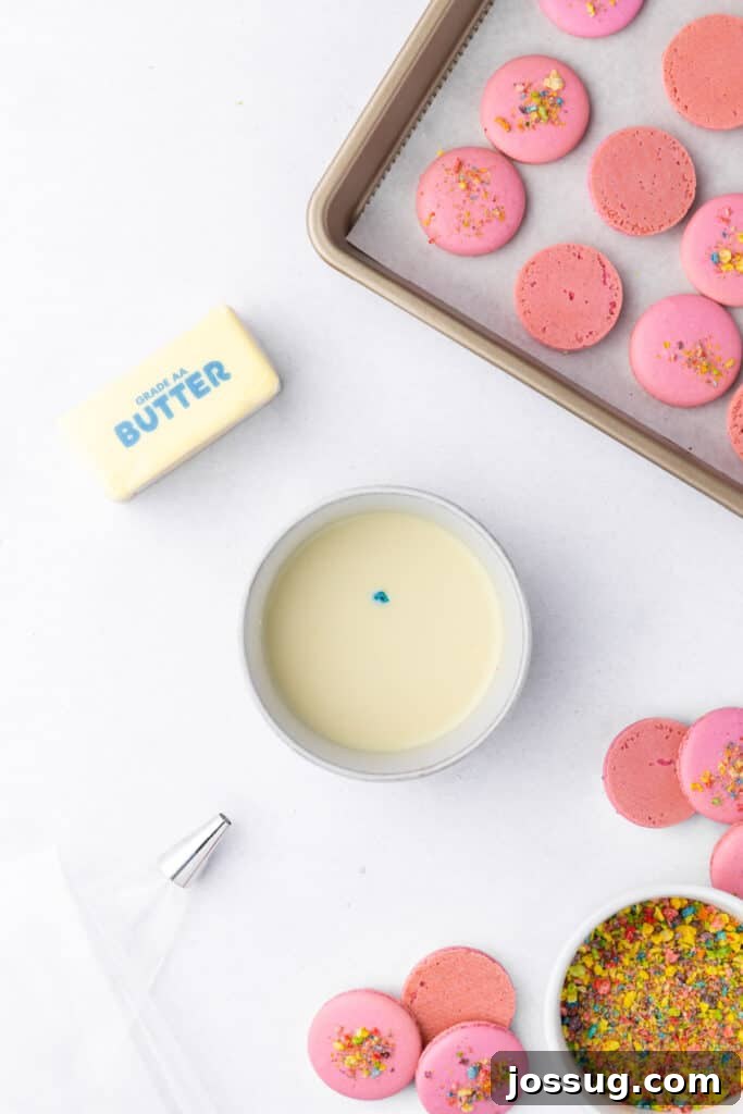 Ingredients for cereal milk and filling including butter, cereal milk in a bowl, crushed Fruity Pebbles, piping bag, and baked macaron shells