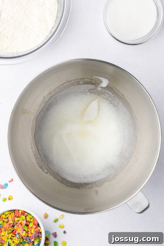 Foamy egg whites beginning to whip in a stand mixer bowl
