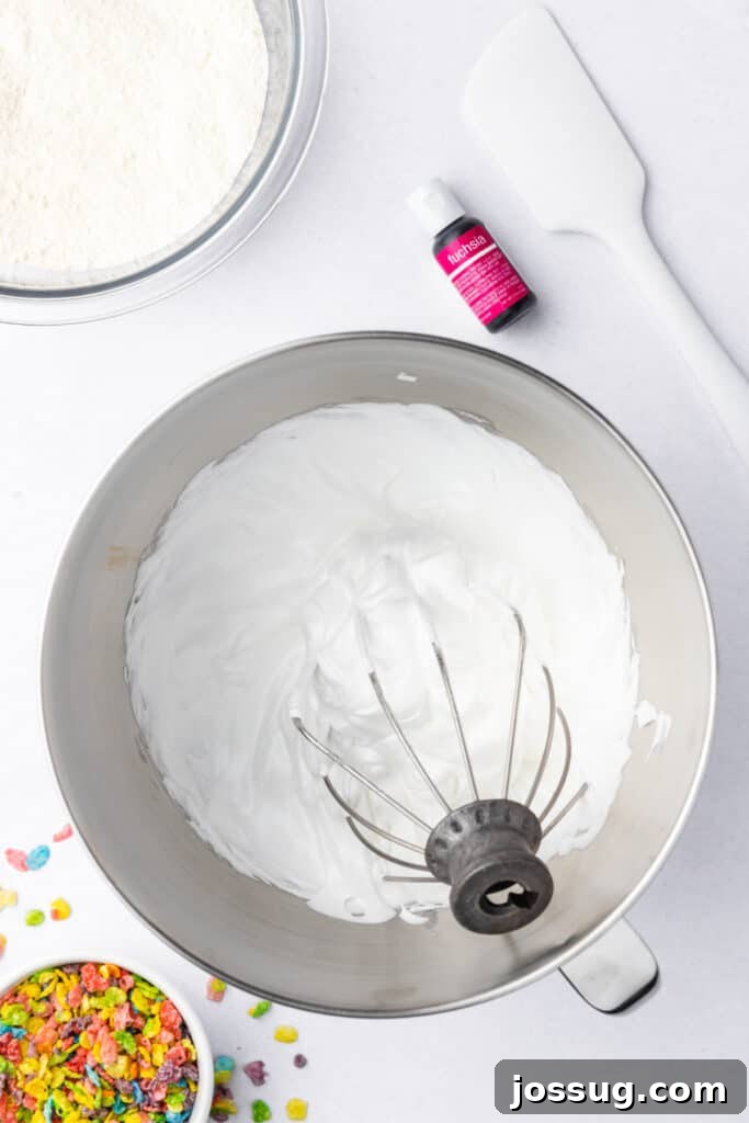 Stiff peak meringue in a stand mixer bowl with a whisk attachment lifted